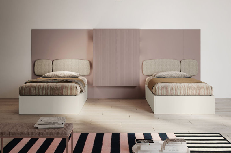 Coppia di letti singoli con pannello murale rosa e pensili centrali abbinati