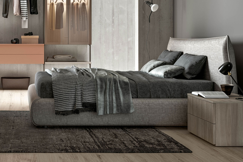 Letto grigio imbottito dentro una camera da letto matrimoniale